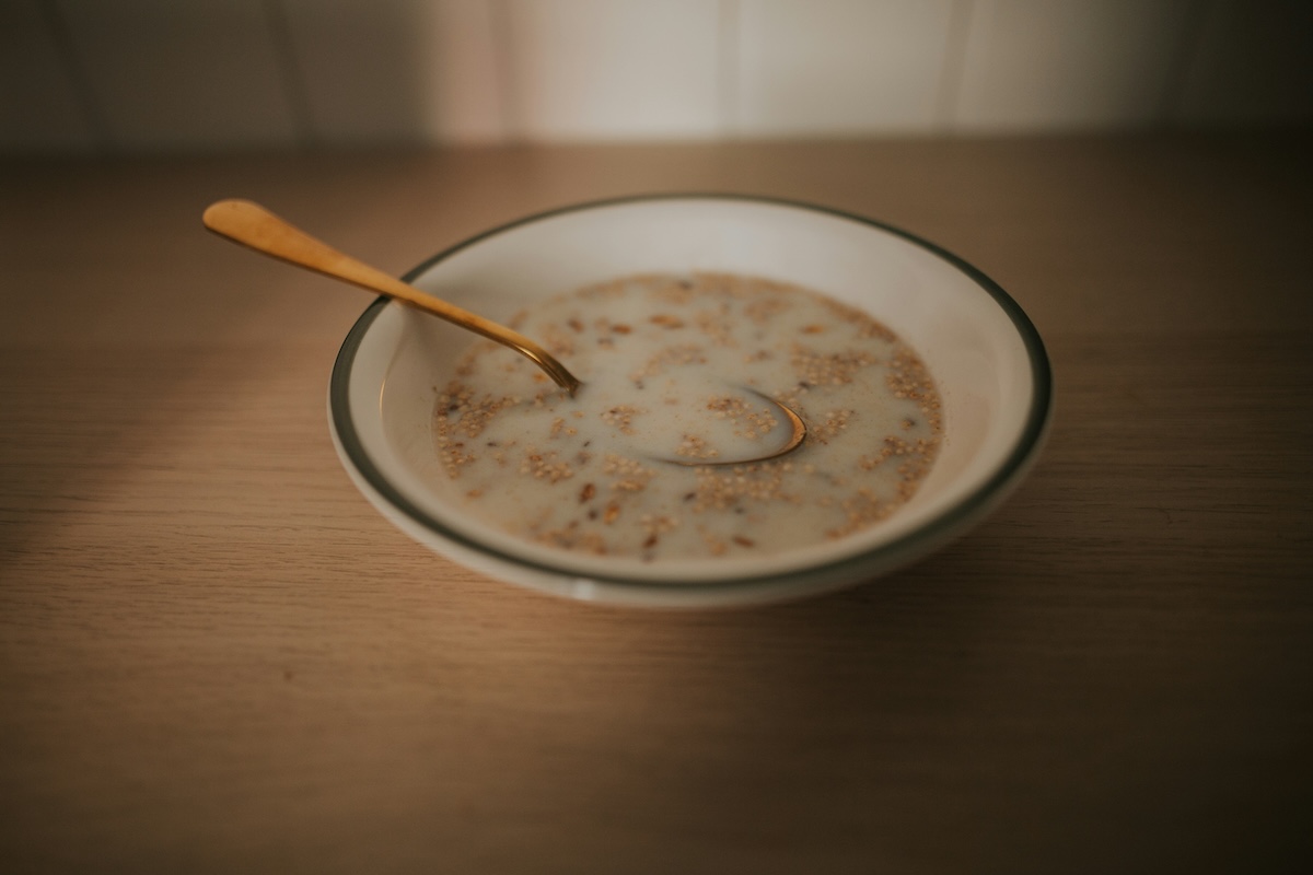 Cereal with oat milk in a white bowl and golden spoon