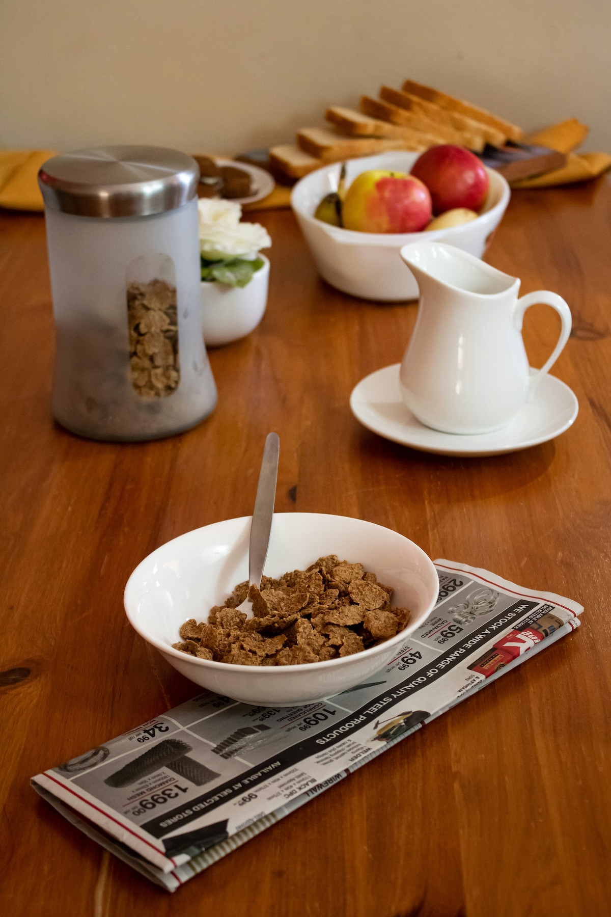 Breakfast table with bowl of bran flakes, milk jug and fruit