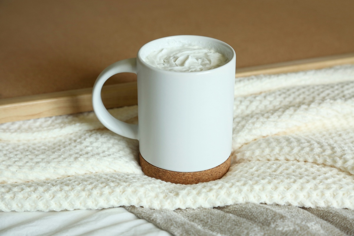 Creamy hot chocolate in a white mug on a cozy blanket