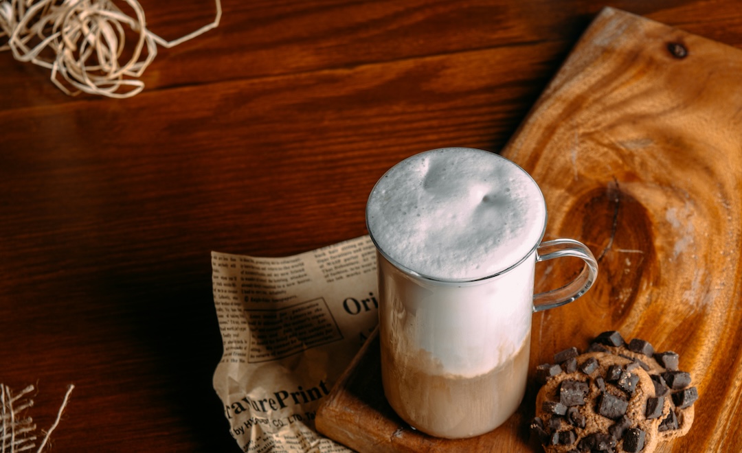 Frothy iced latte with beautiful foam on a wooden serving board