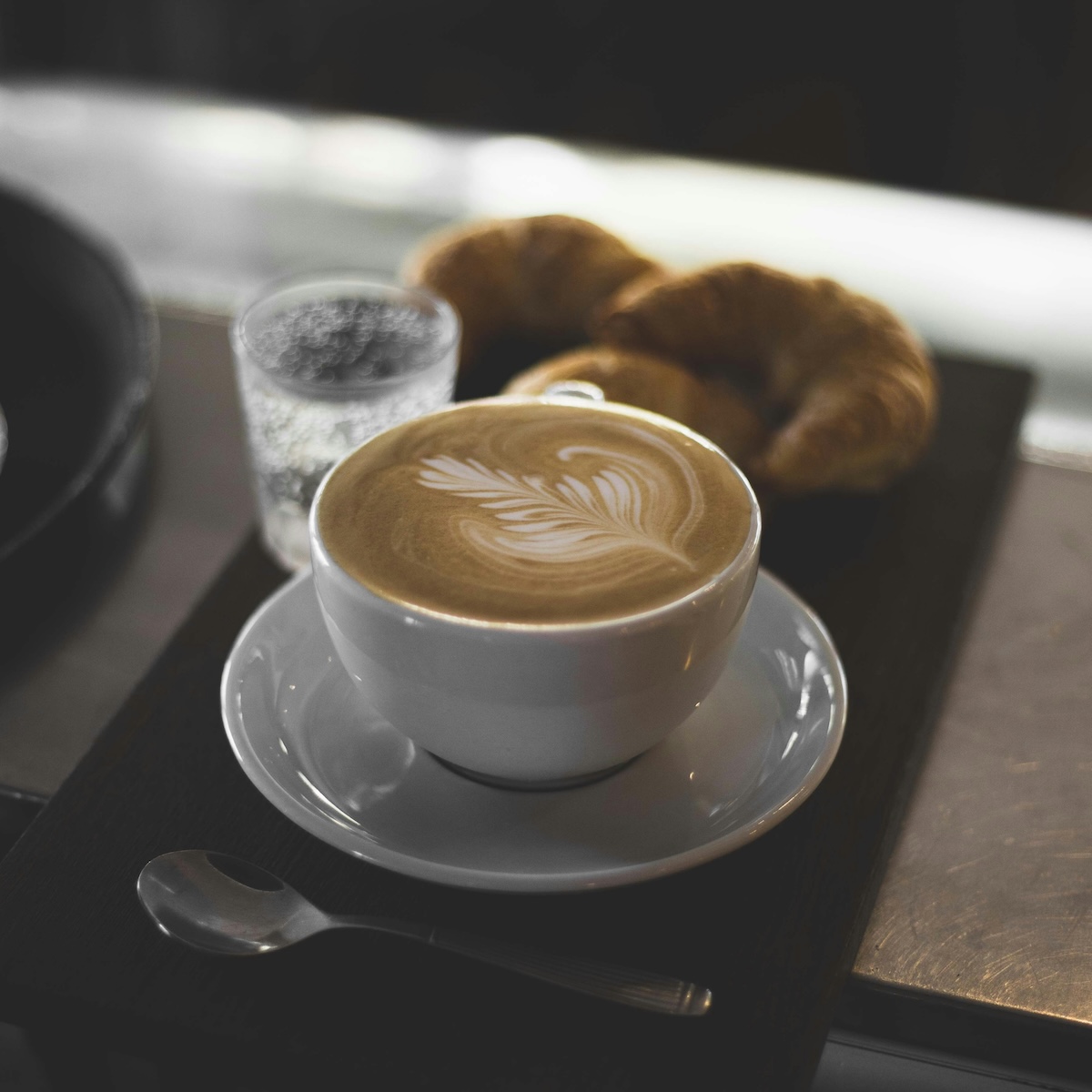 Plant milk latte served with fresh croissants in café setting