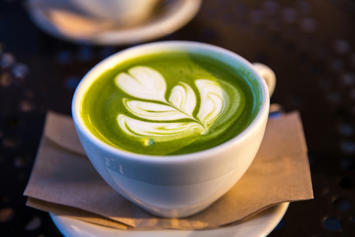 Close-up of matcha latte with beautiful leaf foam art in white ceramic cup