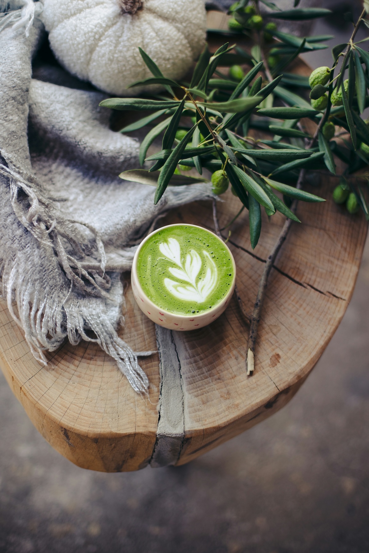 Vibrant green matcha latte with perfect foam art on rustic wooden board