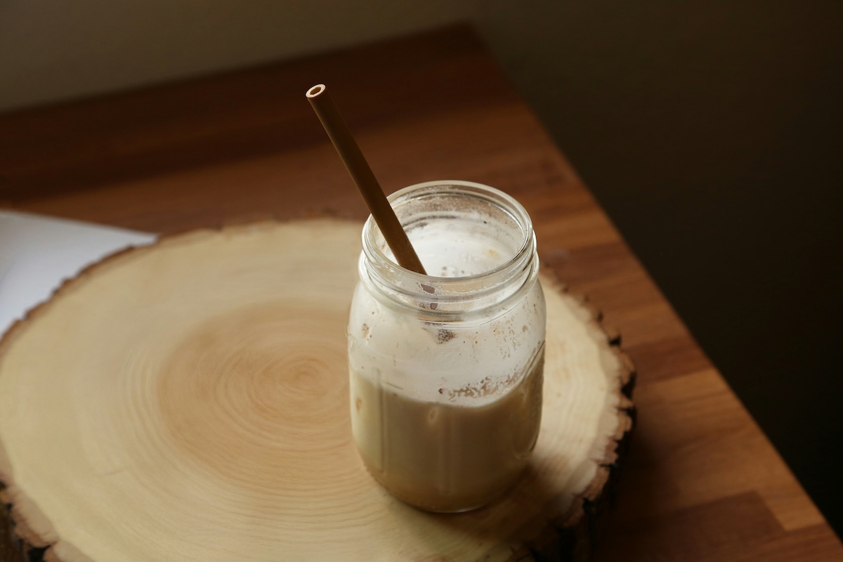 Plant-based milk in glass jar with reusable straw on wooden cutting board