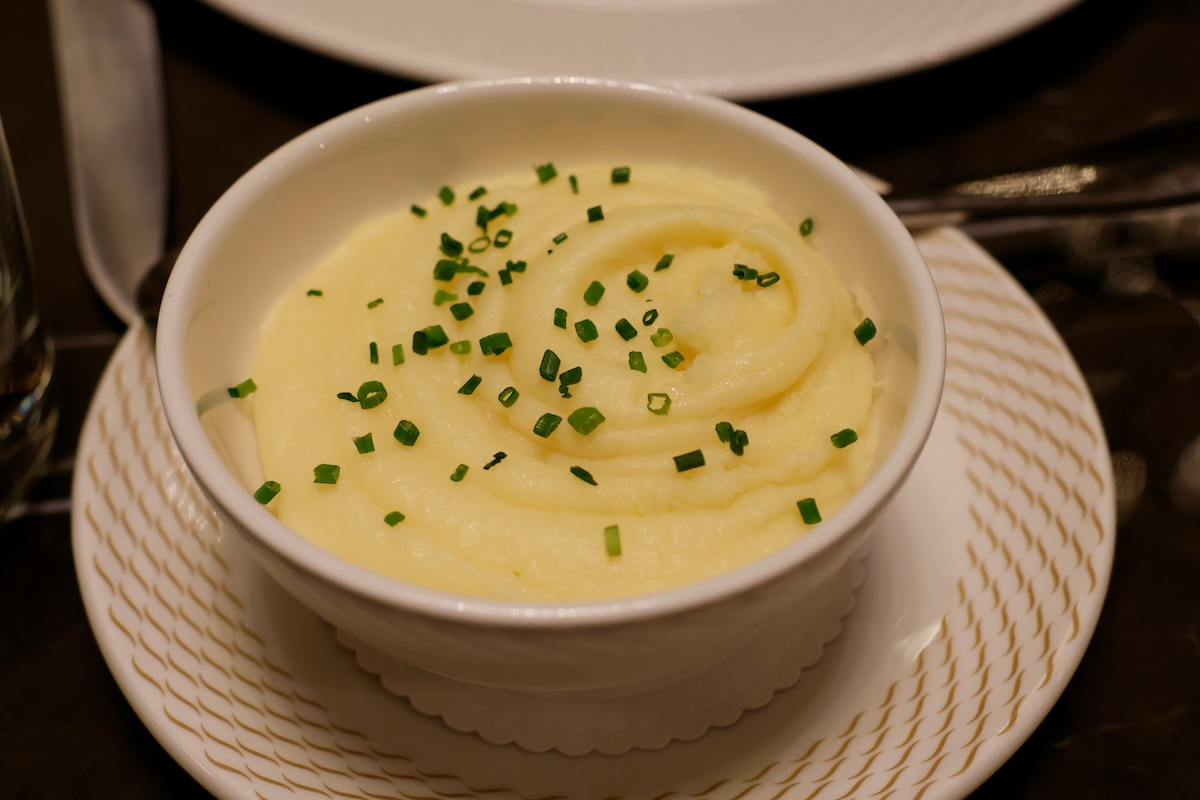 Creamy mashed potatoes being served with wooden spoon