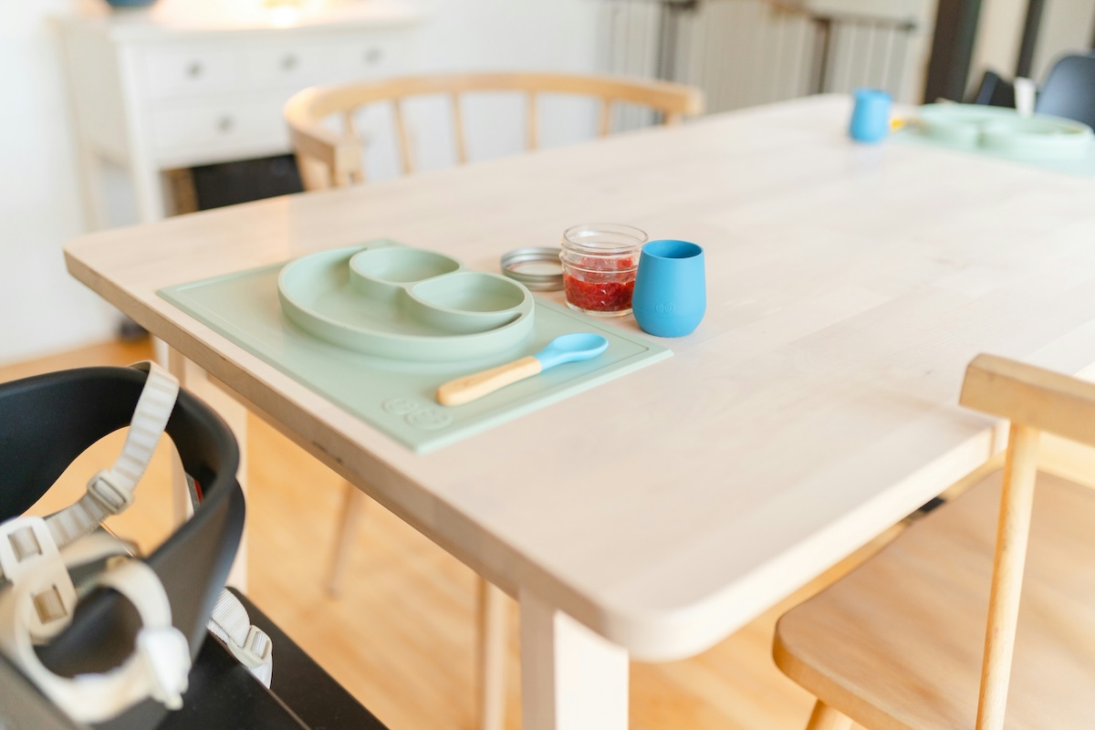 Toddler meal setup with sippy cup, plate, and utensils on highchair tray