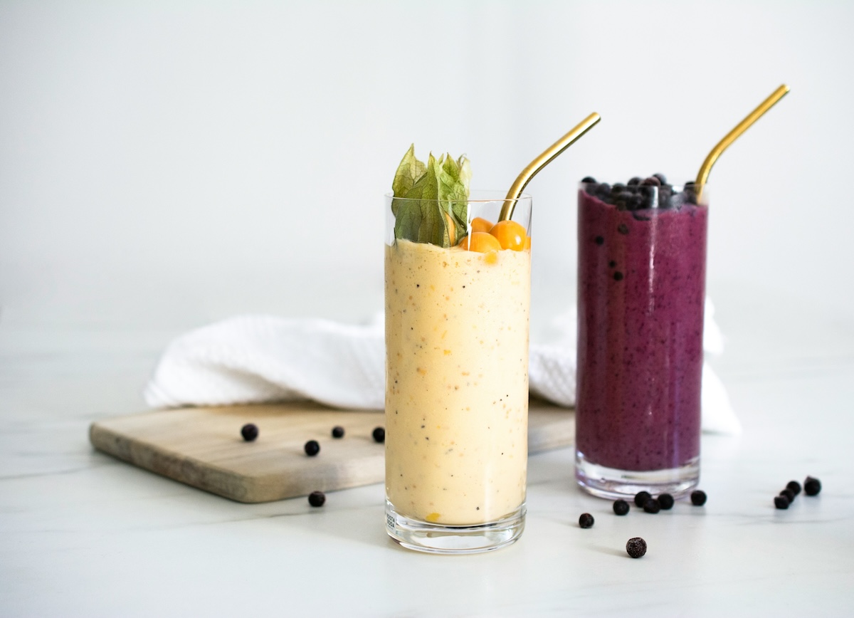 Two smoothies with gold straws - yellow mango and purple berry